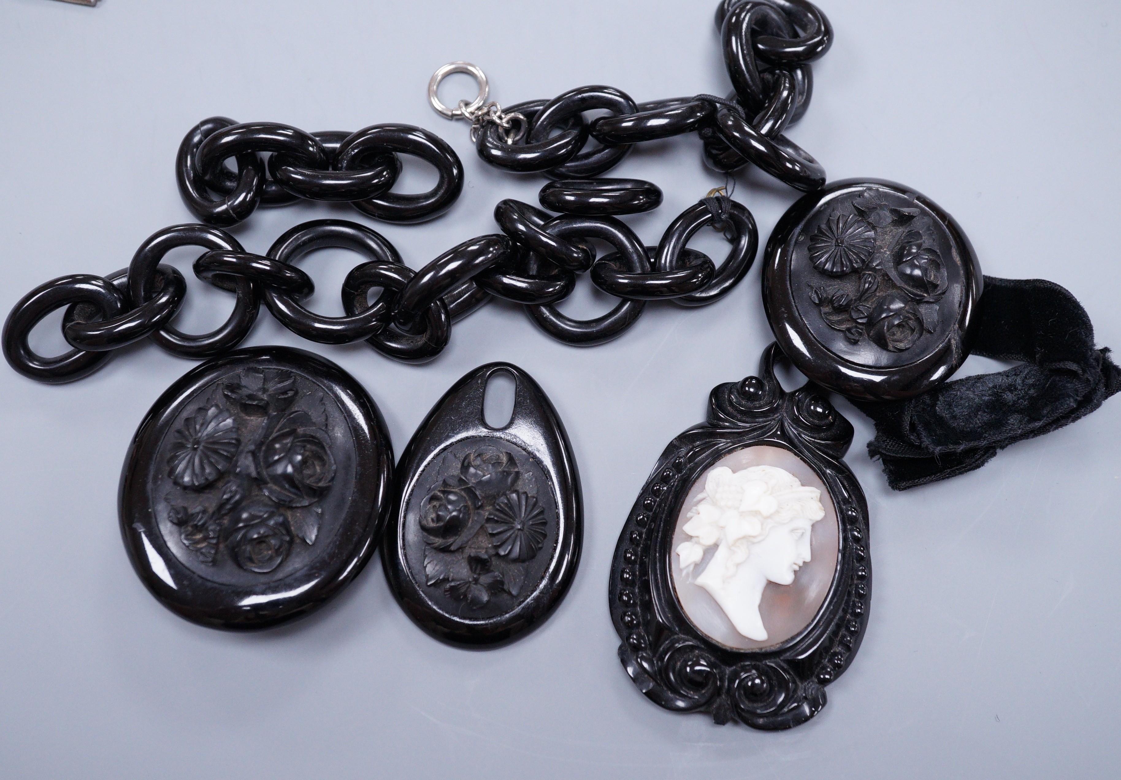 A Victorian floral carved jet brooch with matching bracelet and incomplete chain necklace and a similar pendant inset with a cameo